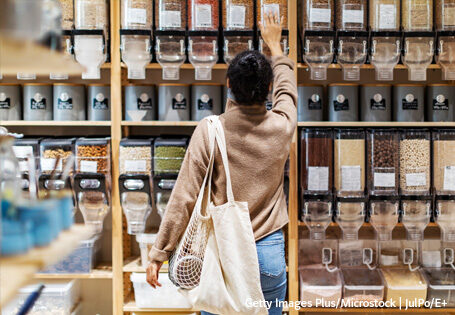 Eine Frau greift nach einem Behälter im Regal eines Unverpackt Ladens