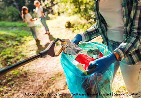 Müllsammelaktion im Wald Greifer mit Müll über einer offenen Mülltüte